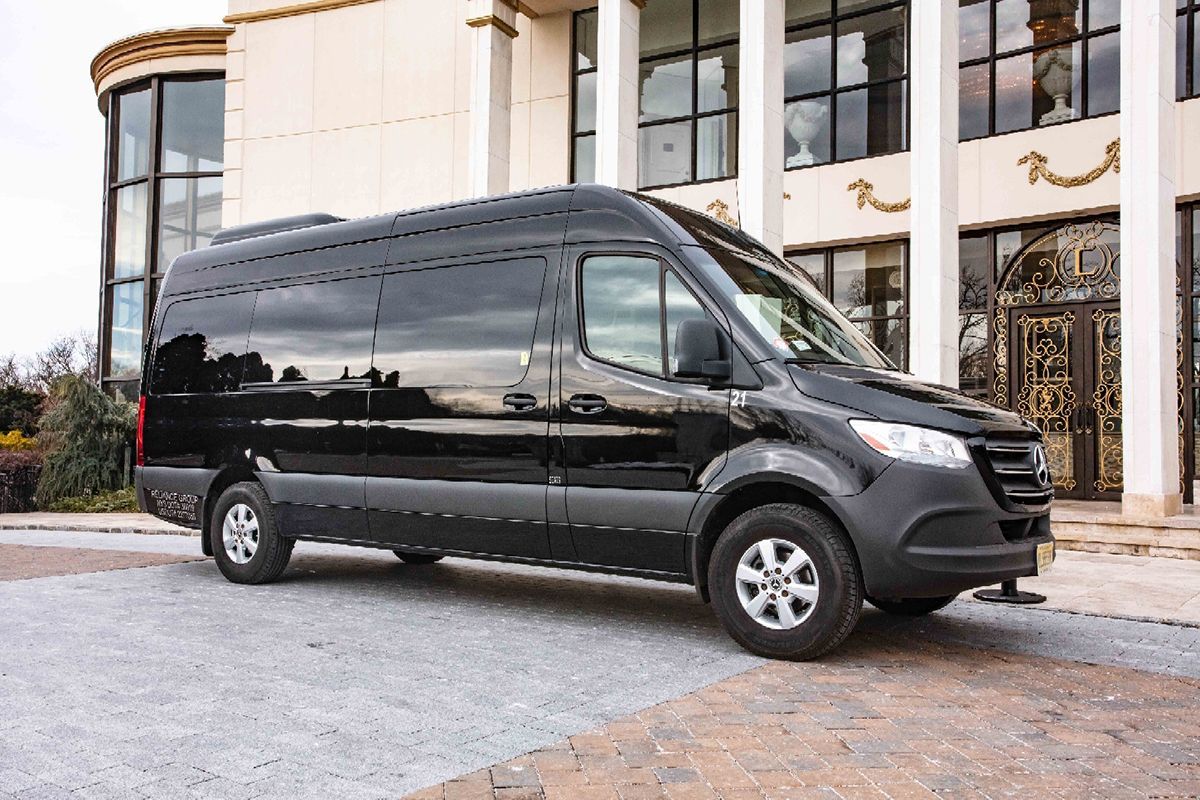 Black passenger van parked in front of a building with columns and large windows.