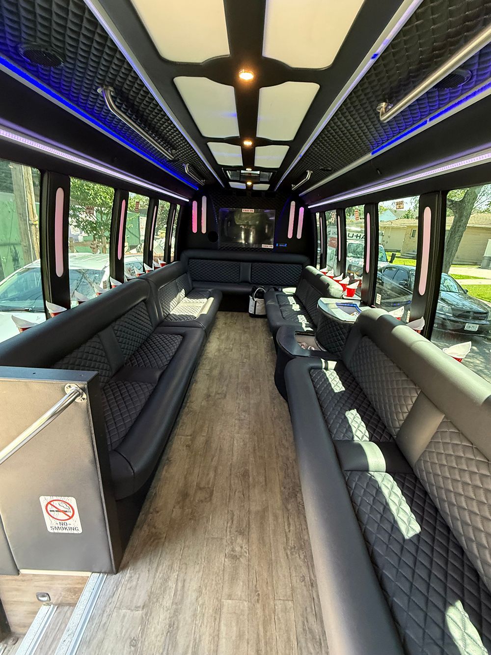 Interior of a luxury party bus with black quilted leather seating and ambient lighting.