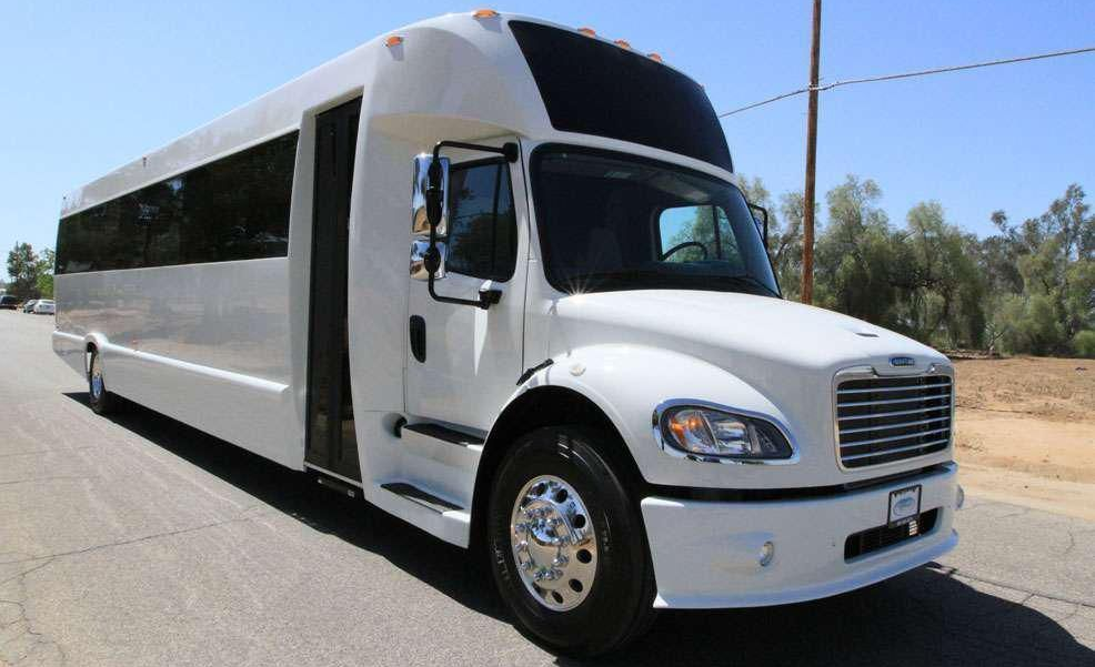 White party bus on a paved road, parked on a sunny day.