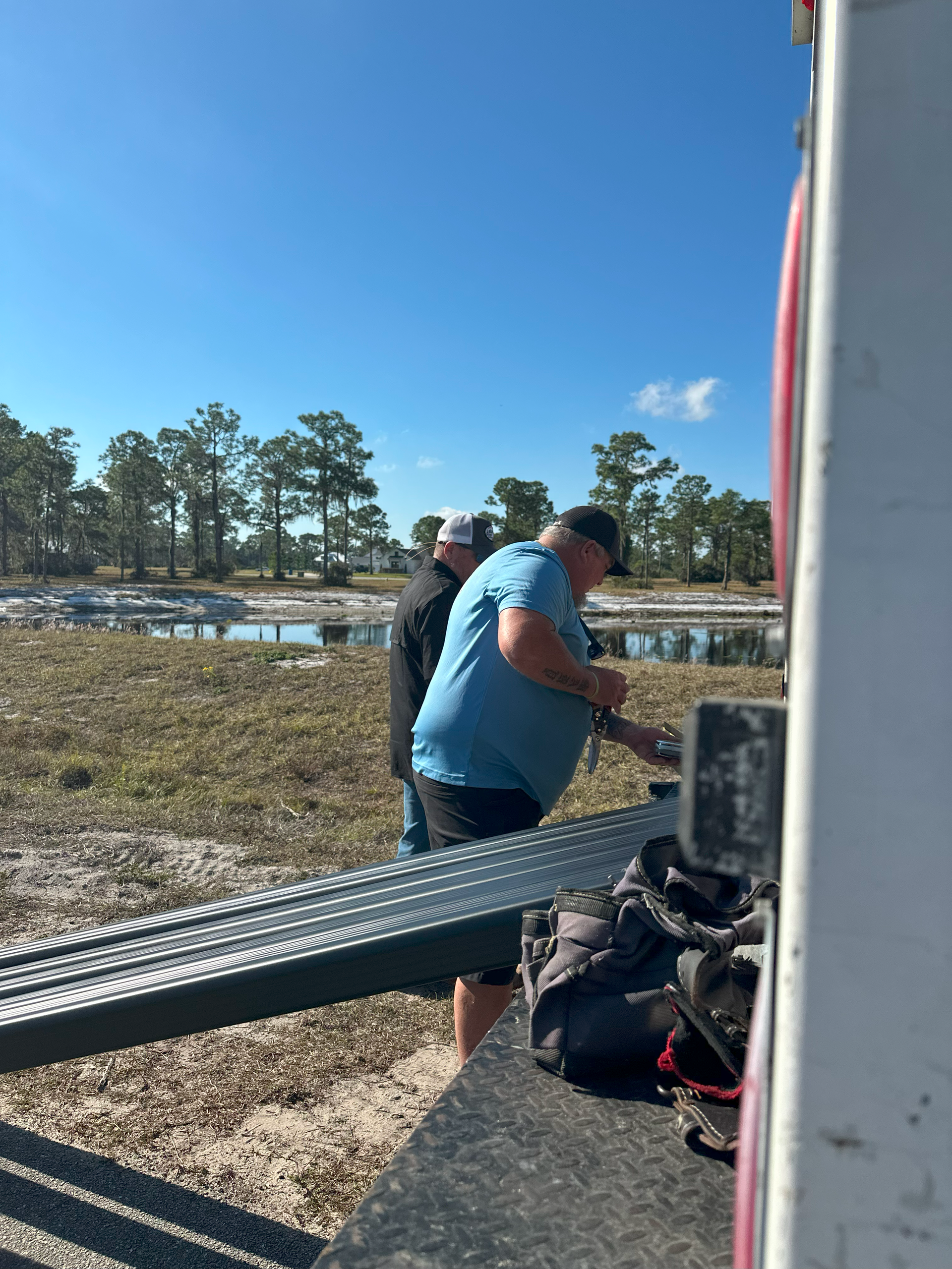 A man in a blue shirt is standing next to another man in a black hat.