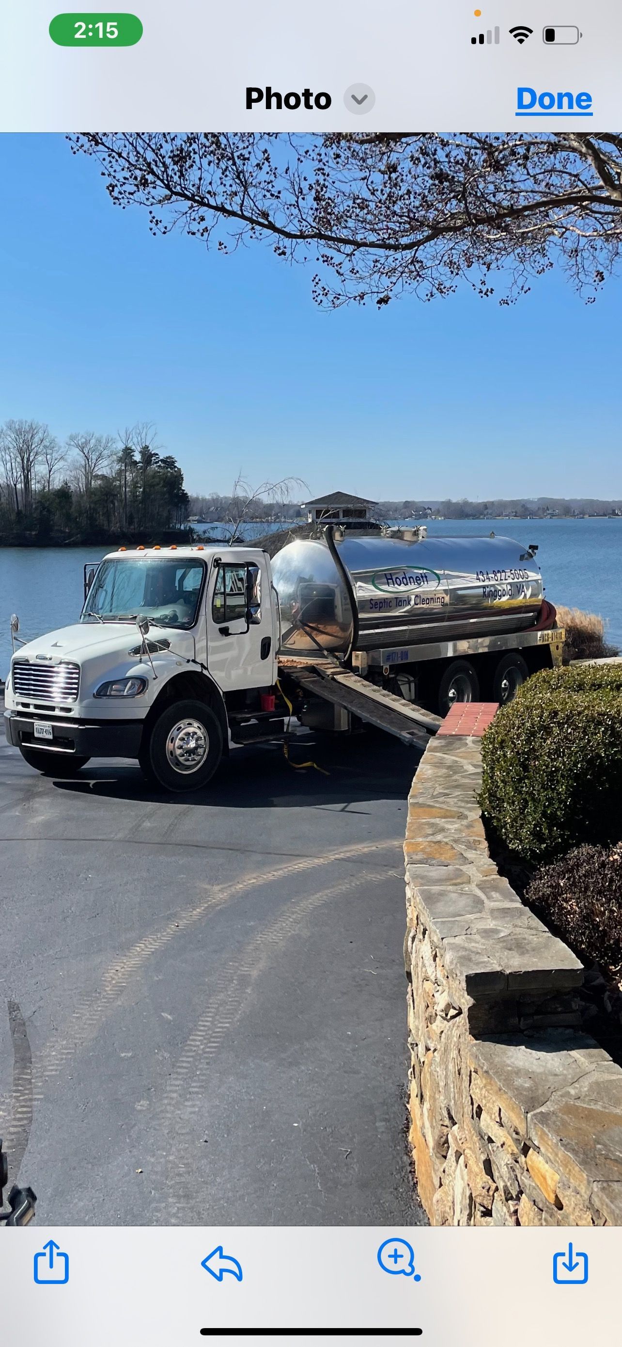 A white truck with a silver tank parked by a body of water.