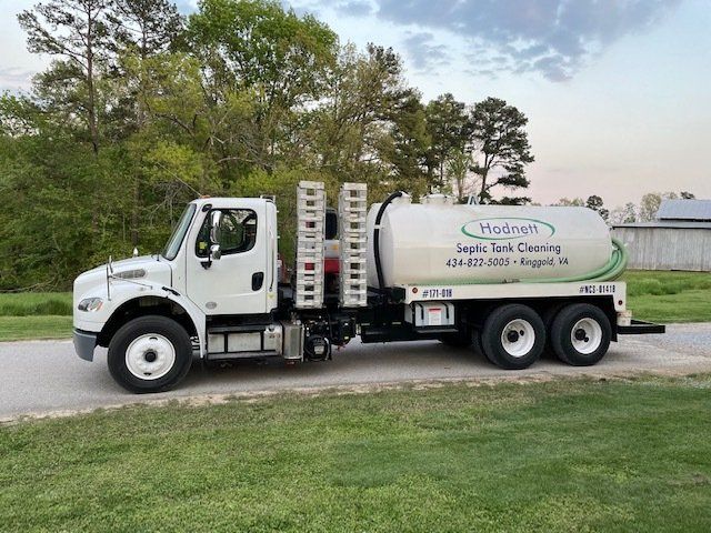 White septic tank truck parked on a road, advertising 