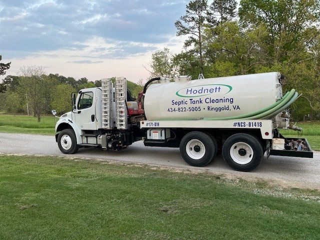 White septic tank truck parked on grass with a rural setting, 