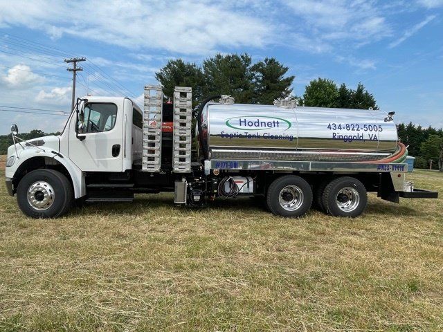 White Hodnett Septic Cleaning truck parked in a field on a sunny day.