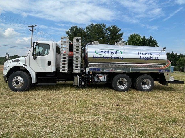 White Hodnett truck with tank for septic services on a grassy field.