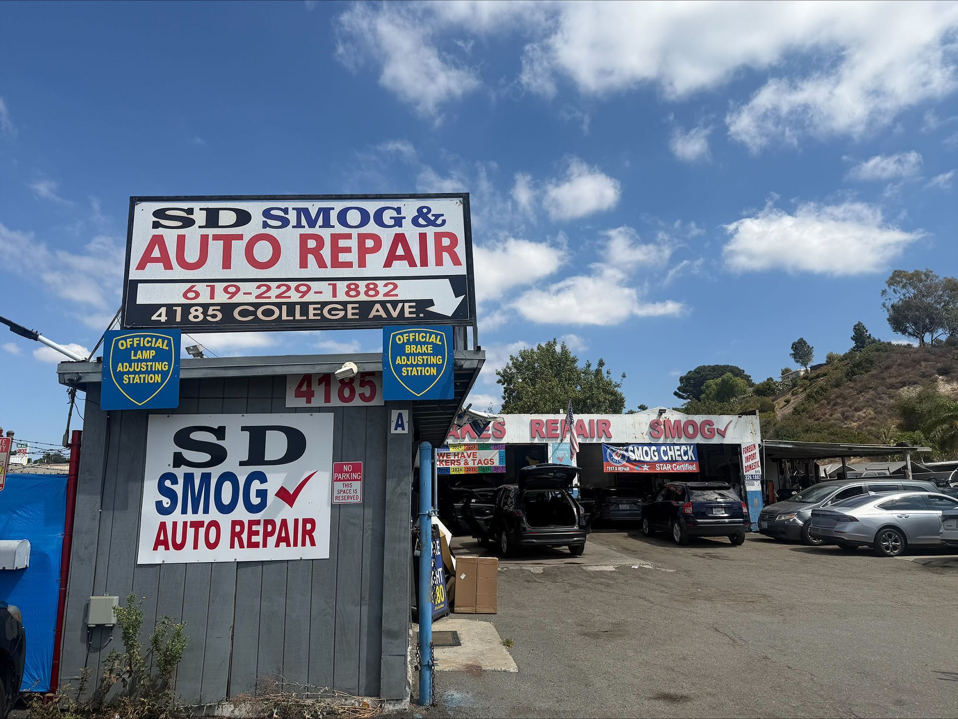 SD Smog & Auto Repair shop with blue building and parked cars under a partly cloudy sky