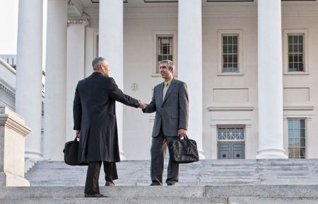 Two men shaking hands on the steps of a building