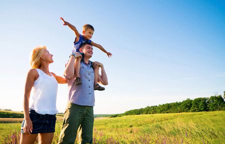 A man is carrying a child on his shoulders in a field.