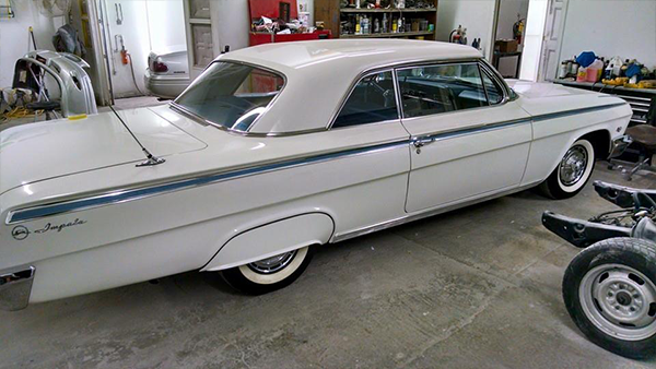 A white car is parked in a garage next to a motorcycle