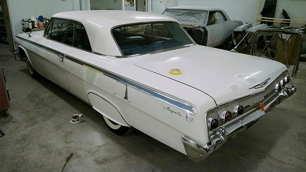White car is parked in a garage next to another car