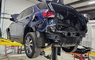 A blue SUV is sitting on a lift in a garage