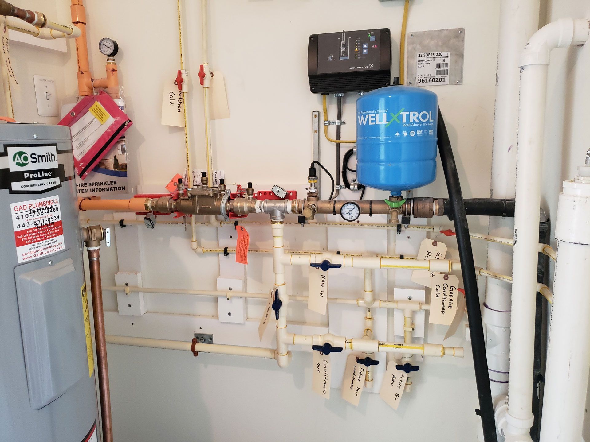 A room with a lot of pipes and a water tank on the wall.