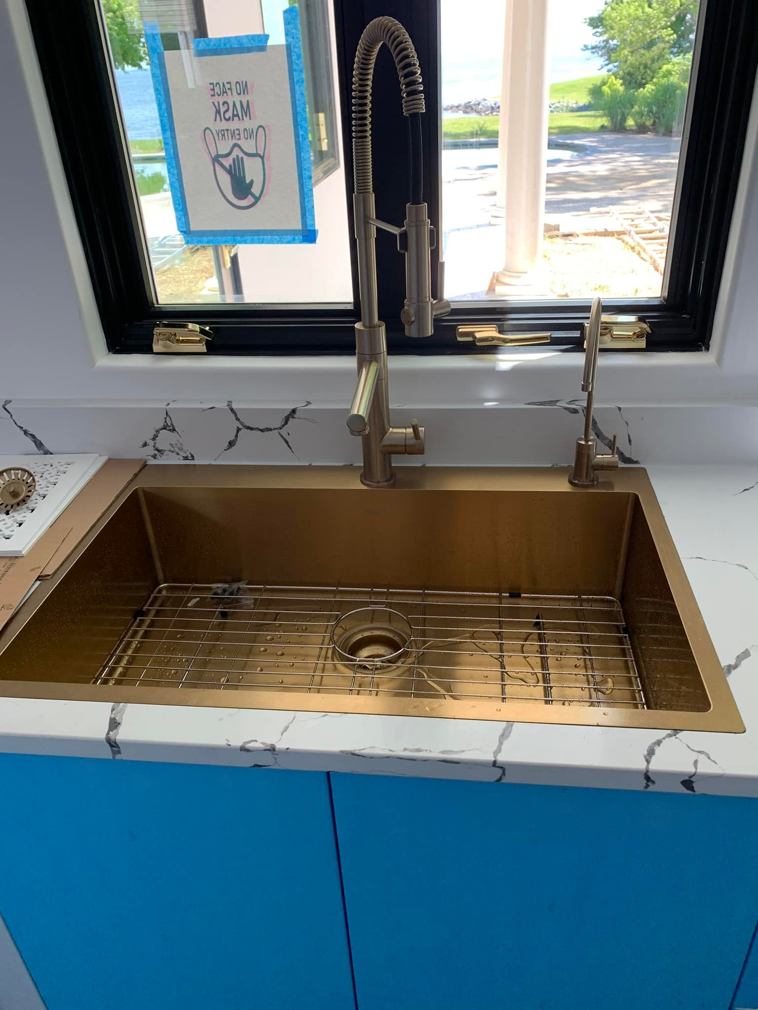 A kitchen sink with a faucet and a window in the background.