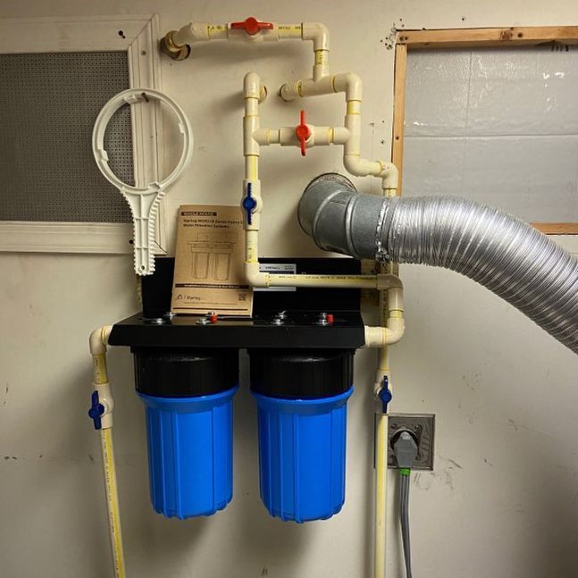 A water filter is hanging on a wall with a hose attached to it.