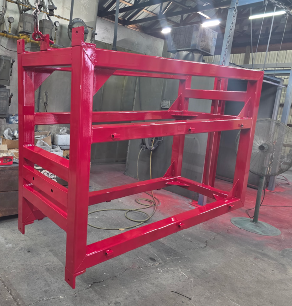 Red metal industrial frame or rack in a workshop, with shelves and hoses in the background