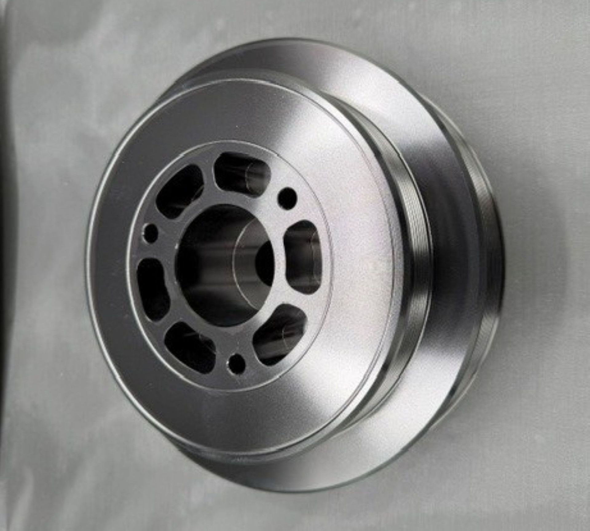 Silver metal wheel rim or pulley with circular cutouts.