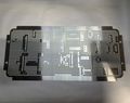Black perforated rectangular metal sheet with many small holes on a light surface.