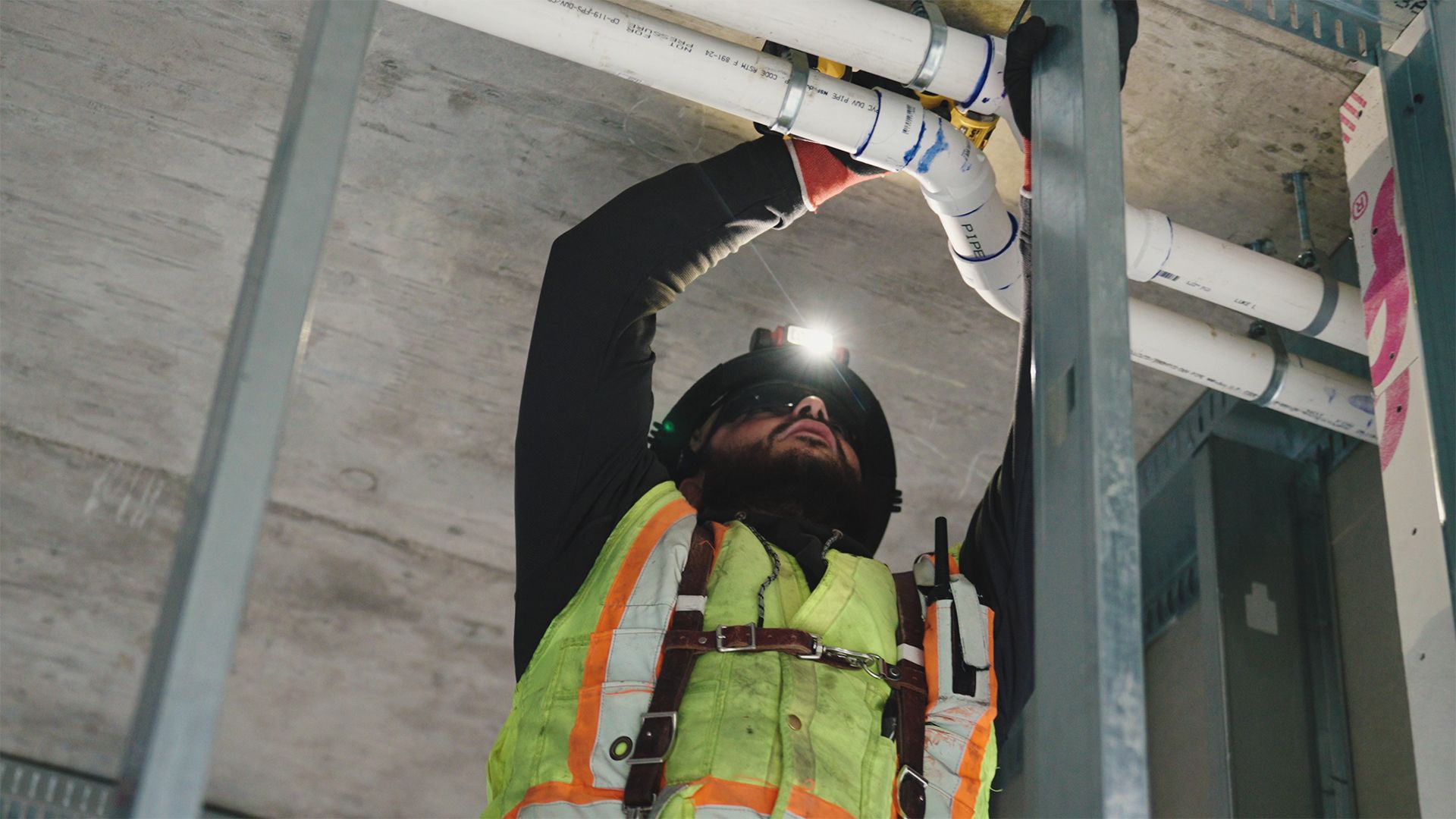 Construction worker installing pipes wearing a headlamp
