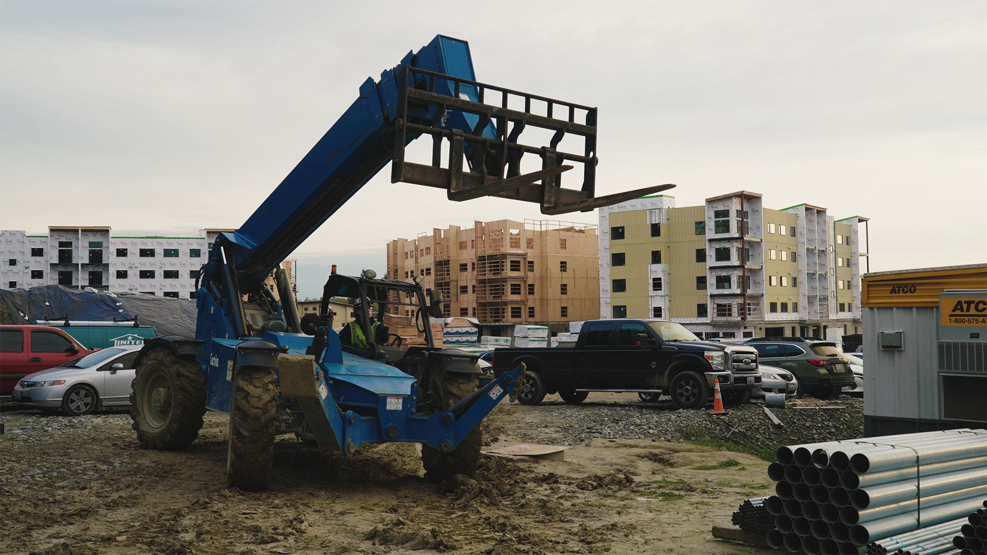 Blue telehandler on a muddy construction site