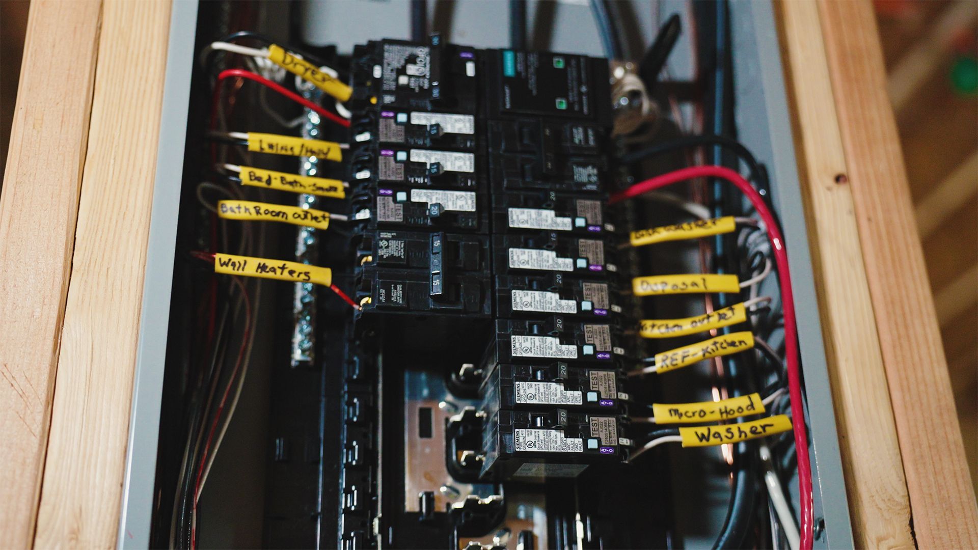 Electrical panel with labeled circuit breakers in a wooden frame