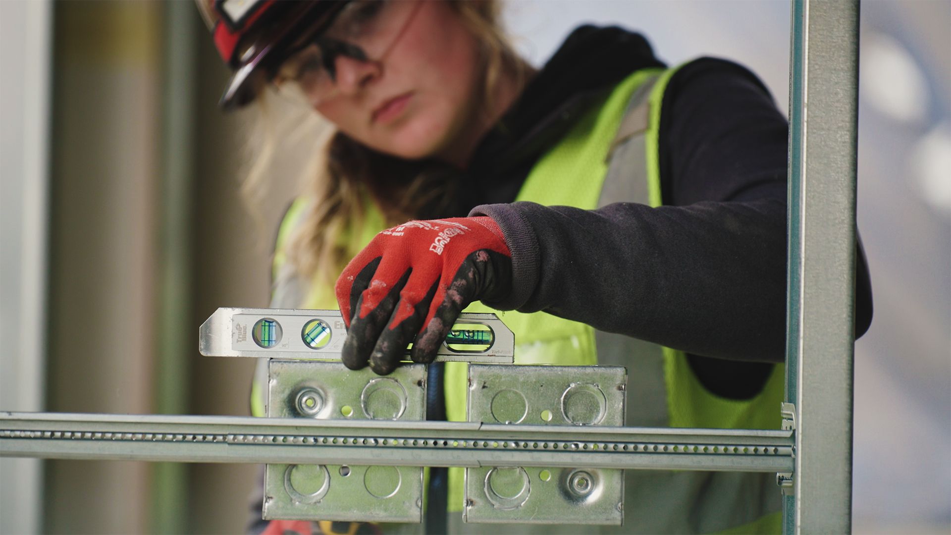 Construction worker using a level on electrical boxes in a metal frame