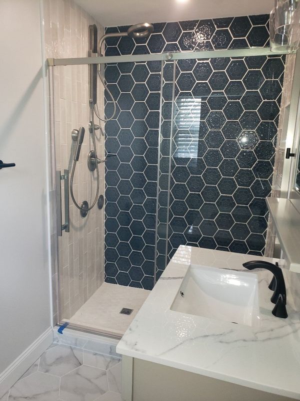 Modern bathroom with a glass shower, hexagon tile wall, and white vanity sink
