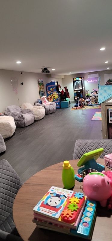 Cozy playroom with beanbags, toys, and a play kitchen under soft ceiling lights