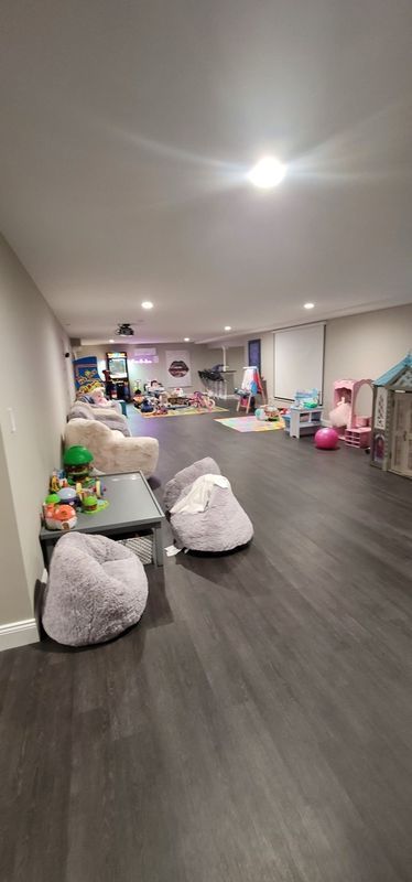 Bright playroom with gray floor, white bean bags, and colorful toys against the walls