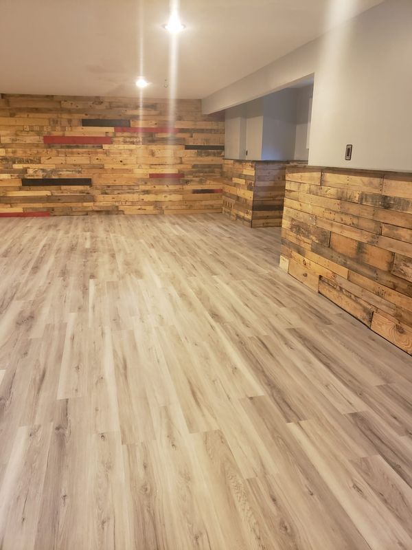 Empty room with light wood flooring, stone accent walls, and ceiling lights
