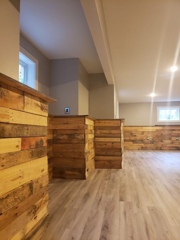 Empty rustic interior with wood paneling, light flooring, and small windows along the wall