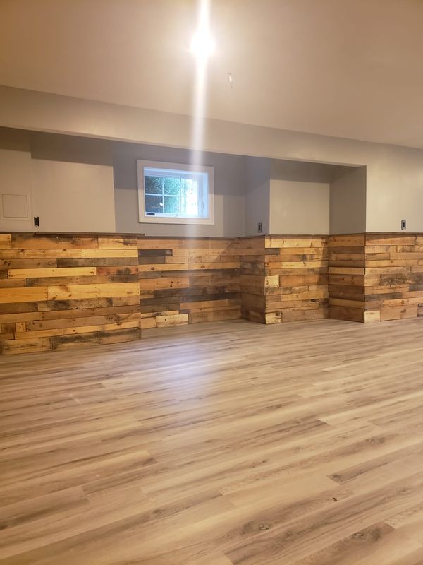 Empty room with wood-look flooring, stone-accent wall, gray cabinets, and a small window.