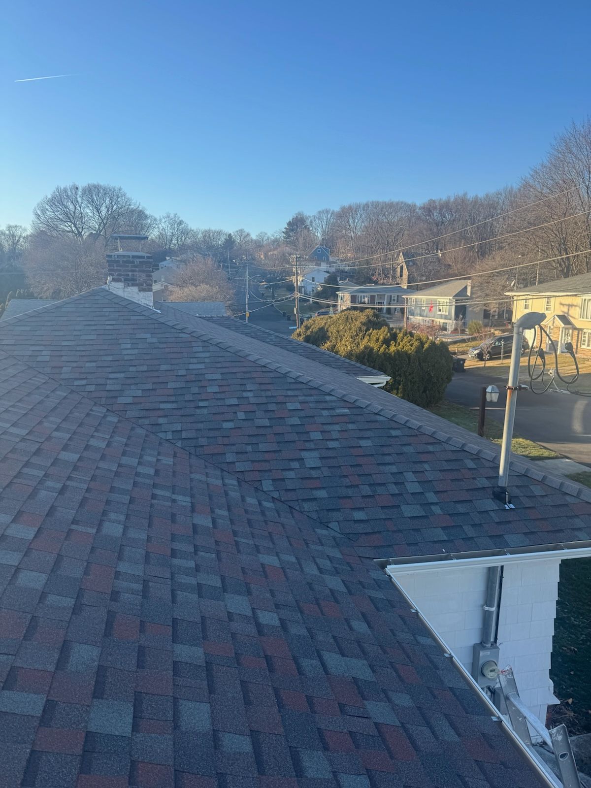 Brick rooftop with a blue sky and a suburban neighborhood in the distance.