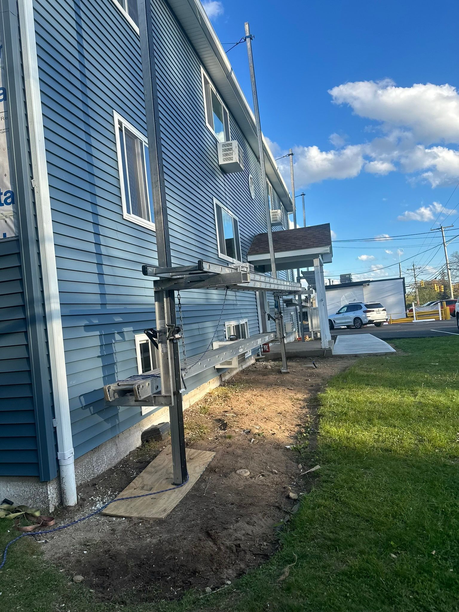 Blue house exterior with a raised metal accessible ramp beside a grassy yard and waterfront view