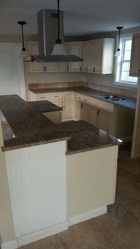 Empty kitchen with white cabinets, dark granite counters, and a window over the sink