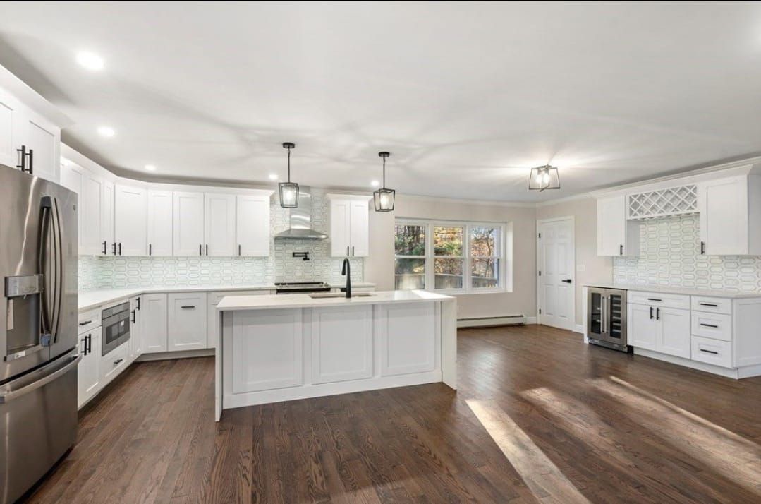 Bright white modern kitchen with island, stainless appliances, and dark wood floors