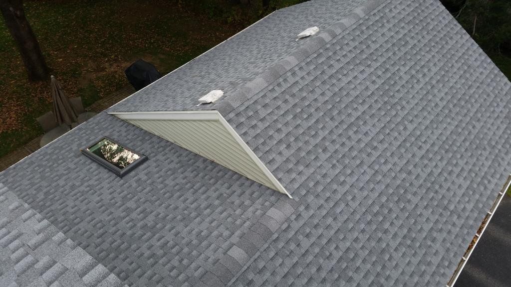 Gray shingled roof with a dormer window and skylight, viewed from above
