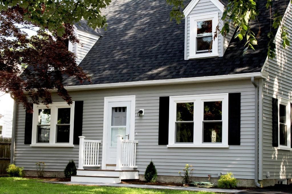 Gray house with black shutters, white trim, and a small front porch under leafy trees