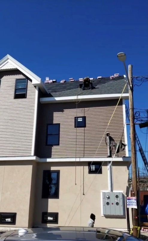 Two-story beige house with rooftop solar panels and utility meters against a clear blue sky.