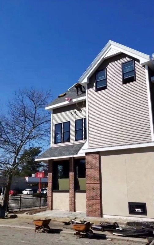 New townhouse exterior with tan siding, brick accents, and small front porch under a clear blue sky