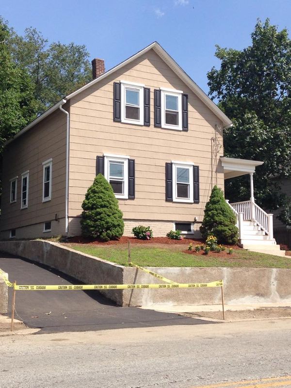 Beige house with white trim and front steps behind yellow caution tape by the sidewalk