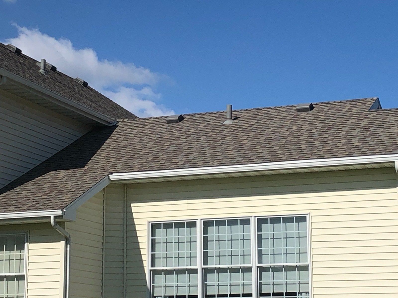Beige house with a brown roof and blue sky.