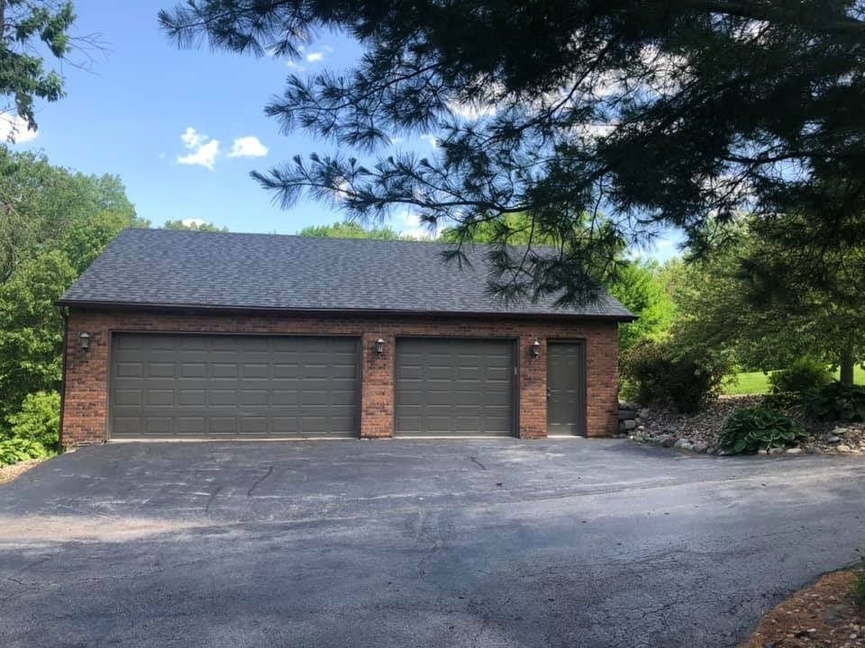 Brick garage with two bays and a small side door, on an asphalt driveway.