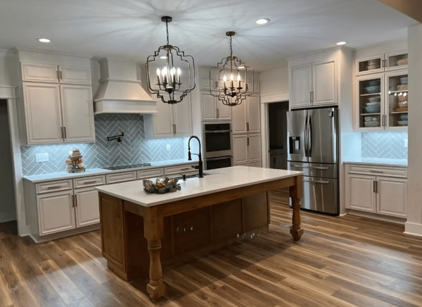 Bright modern kitchen with white cabinets, large island, pendant lights, and stainless steel appliances