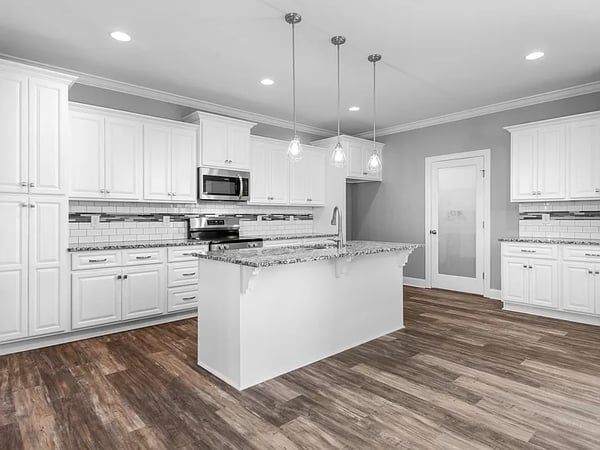 Bright modern kitchen with white cabinets, granite island, stainless appliances, and wood floors