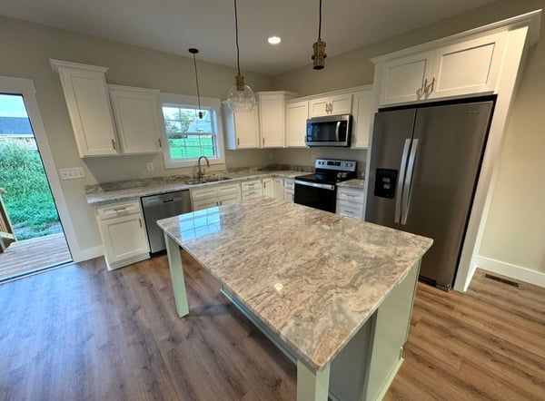 Bright modern kitchen with white cabinets, stainless appliances, and a large marble island