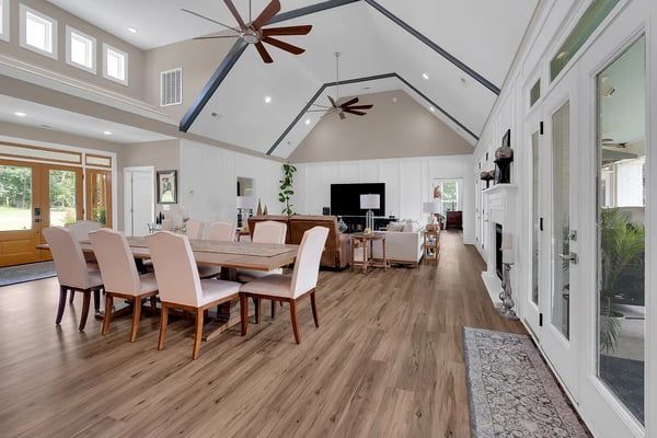Spacious modern dining and living room with vaulted ceiling, wood floors, and large windows