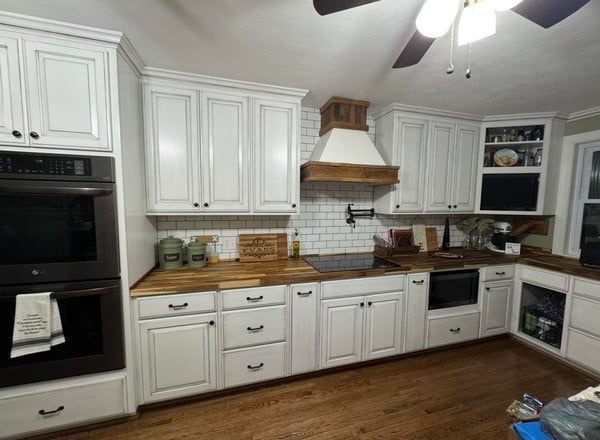Bright white kitchen with wood countertops, stainless appliances, and hardwood floors.