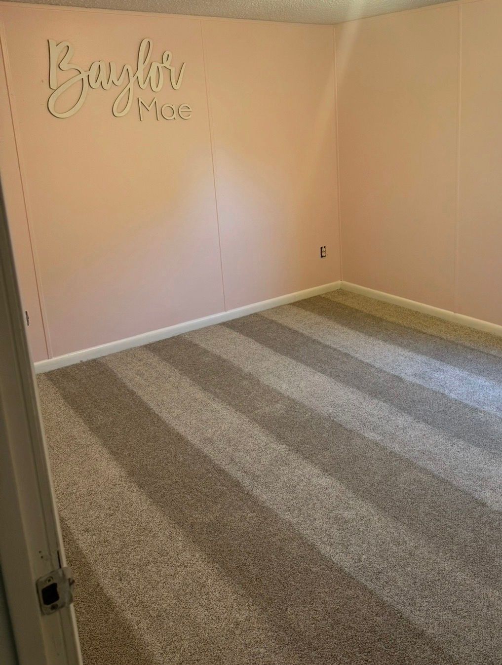 Empty pink bedroom with beige carpet and striped sunlight on the floor
