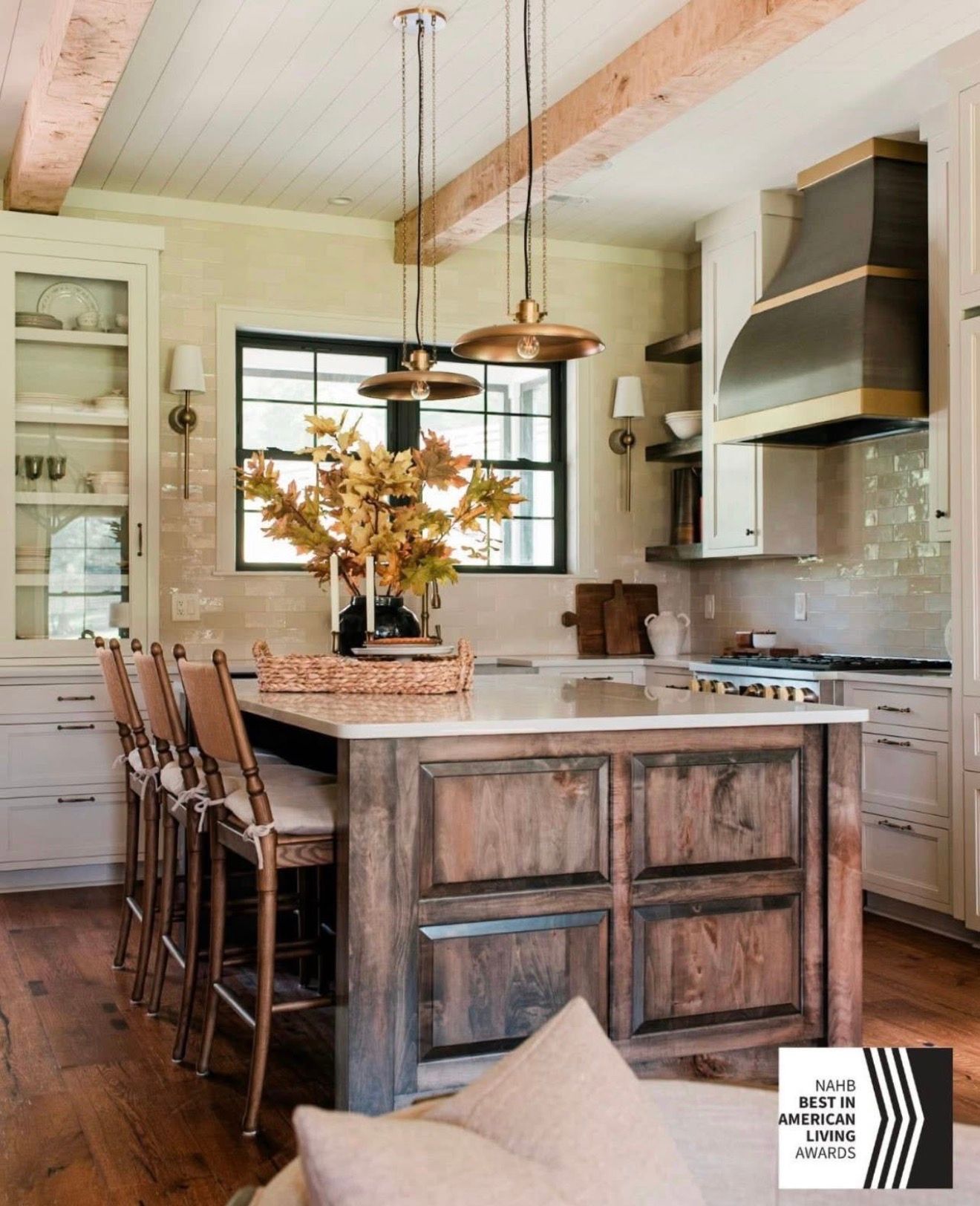 Rustic kitchen with wood island, hanging lights, bar stools, and open shelves in a bright farmhouse interior