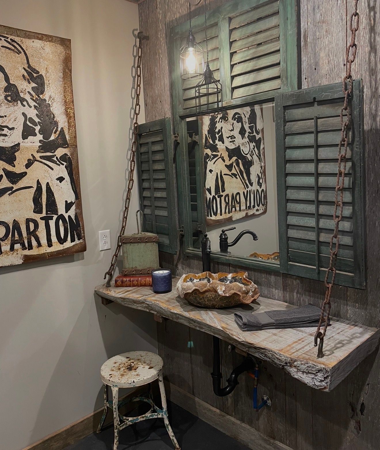 Rustic vanity with green shutters, a small mirror, sink, and wall art in a narrow room.